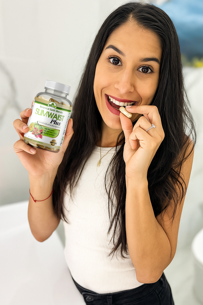 Mujer sonriente tomando cápsula de SlimWaist Plus y sosteniendo el frasco del suplemento